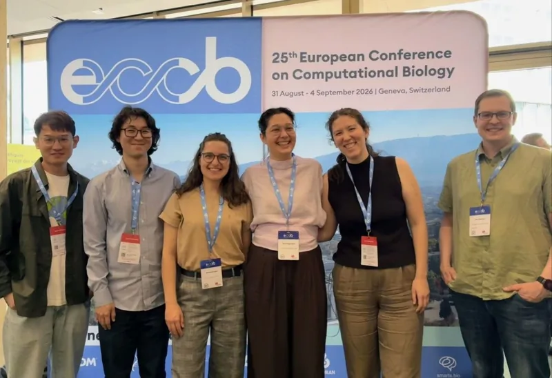 Six members of the group standing in front of the ECCB 2026 conference banner, which reads 25th European Conference on Computational Biology, 31 August - 4 September 2026, Geneva, Switzerland